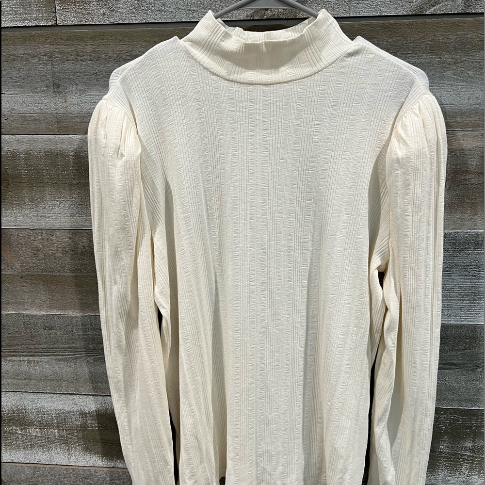 Mock turtle neck in cream with pleated puff shoulders.